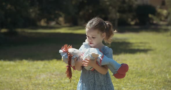 Cute little girl wearing a blue dress playing alone outdoors