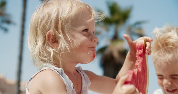 Closeup of Little Girl Playing with Watermelon Slice and Eat It on Summer Day