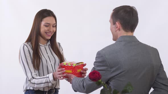 Man in Suit Gives a Girl the Box with Present and Rose