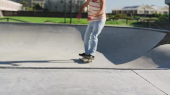 Caucasian man riding and jumping on skateboard on sunny day