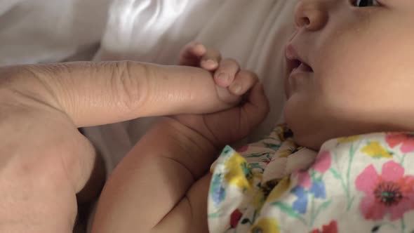 Baby girl holding parents finger