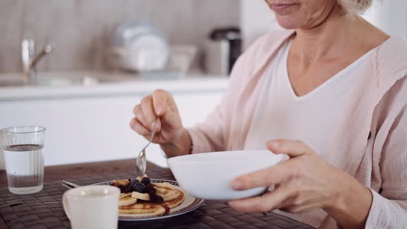 Slow motion shot of mature woman preparing pancake with nuts