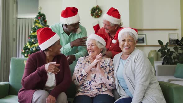 Happy diverse senior friends in santa hats on video call at christmas time