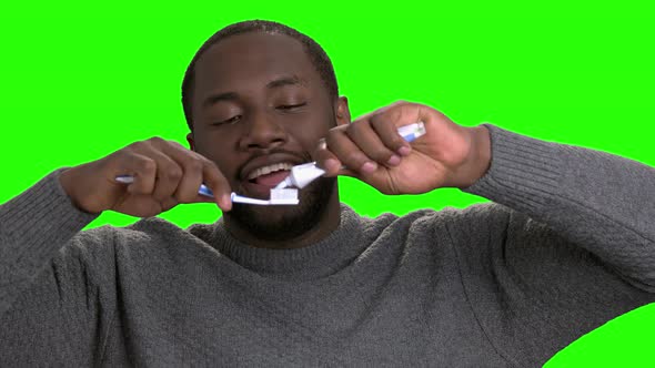 Dark-skinned Man Applying Toothpaste on a Toothbrush.