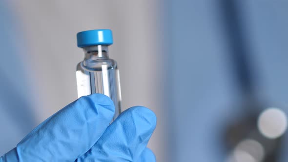 Doctor in Blue Latex Gloves Holding Glass Vial with Vaccine