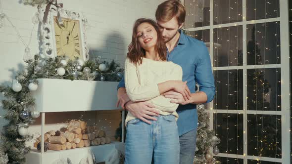 Smiling beautiful woman and her handsome boyfriend posing in New Year interior