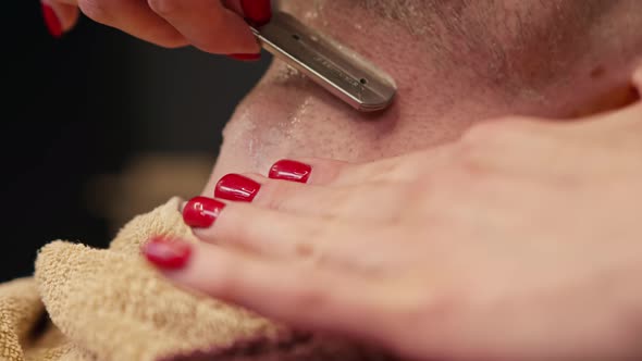 Barbershop: a woman barber shaves a man using a straight razor