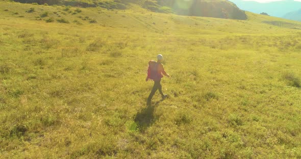 Flight Over Backpack Hiking Tourist Walking Across Green Mountain Field. Huge Rural Valley at Summer