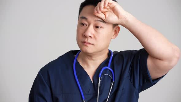 Tired Asian doctor putting off gloves