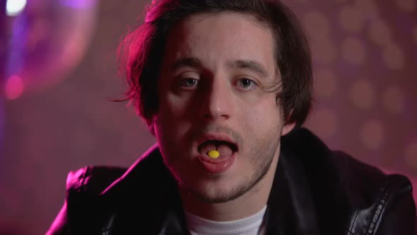 Guy Holding Narcotic Pill on Tongue, Swallowing Drugs and Smiling at Camera