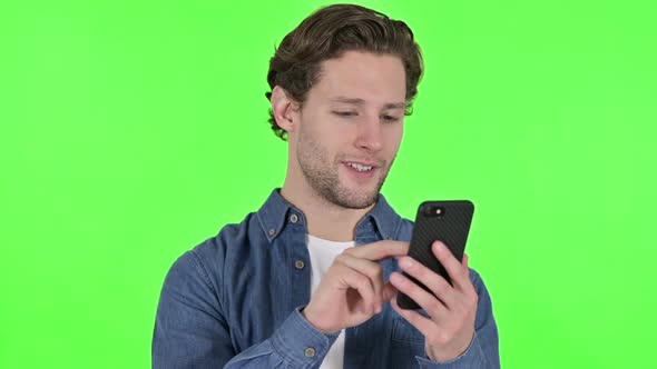 Portrait of Young Man Using Smartphone on Green Chroma Key