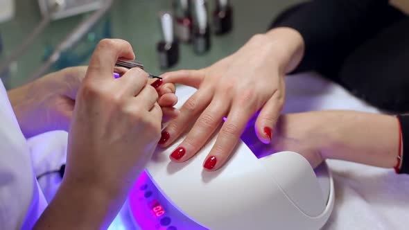 A Beautician Applies Red Nail Polish To a Young Womans Nails