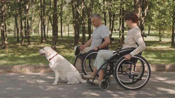 Wheelchair Couple with Dog on Walk in Park