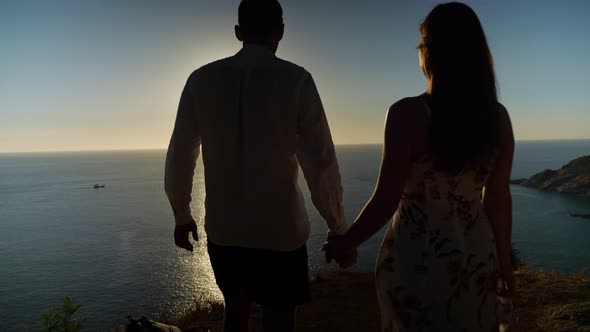 Couple Holding Hands Goes To Viewpoint Edge at Wonderful Sunset