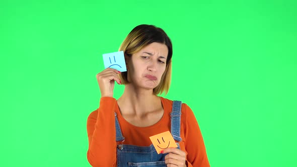 Girl Holding Paper Stick Expressing Awful Mood Then Takes Another Expressing Good Mood. Green Screen