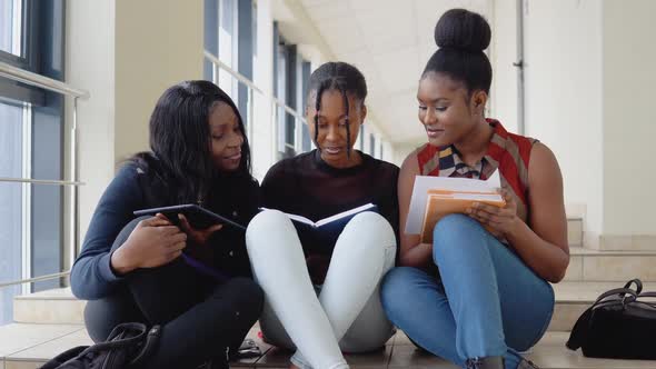 A Group of African American Students Sit on the Floor with Books and a Tablet at the University