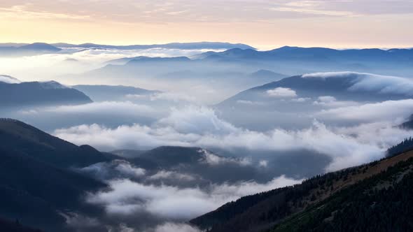 Clouds spill over the tops of the hills in the light of the rising sun, Mystical Atmosphere.