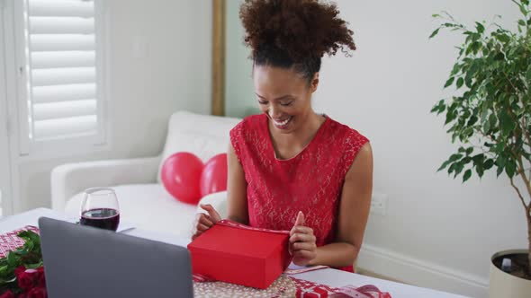 Mixed race woman on a valentines date video call, opening gift