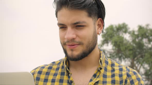 Handsome man siting on stairs using laptop outdoors