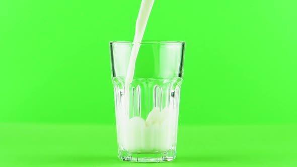 Milk Pouring Into Faceted Glass Close Up Isolated on Light Green Background Slow Motion