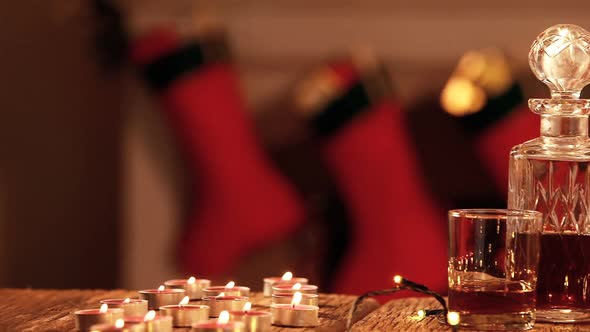 Whisky decanter, tealight candle and christmas lights on plank