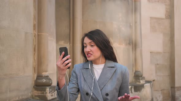 Young Woman Wearing Earphones Making a Video Call Smiling Talking Relaxed on the Street City