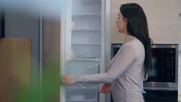 Female Caucasian Buyer Opening Fridge in Store Looking Inside