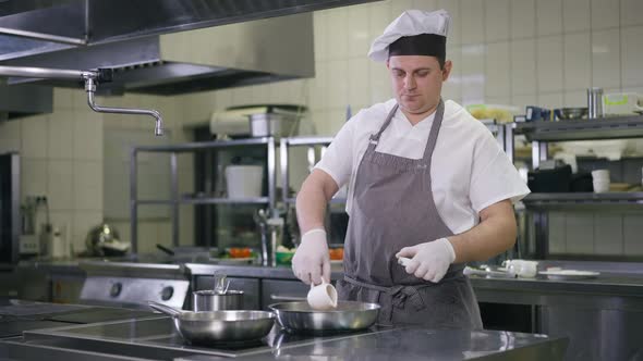 Concentrated Caucasian Professional Cook Pouring Vegetable Oil in Cooking Pan in Slow Motion Setting