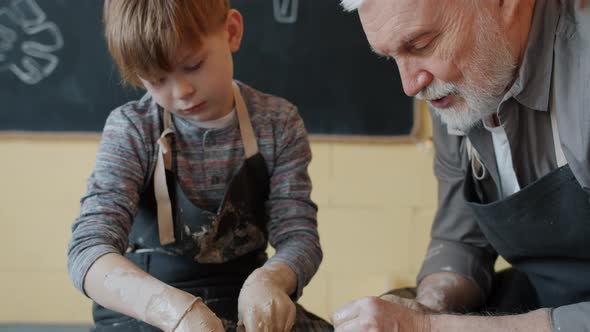 Professional Potter Teaching Little Student To Work with Throwing-wheel During Pottery Class