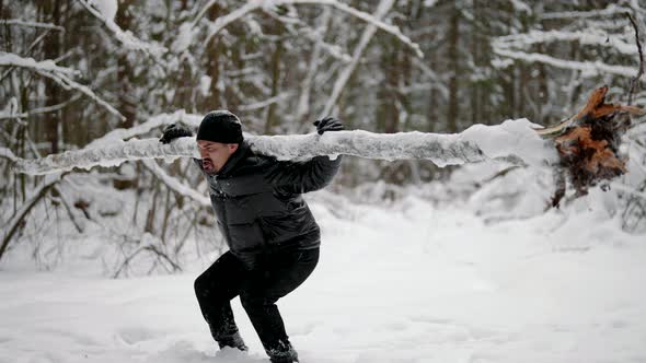 Training in Nature in Winter Day Middleaged Man in Black Clothes is Holding Log on Shoulders