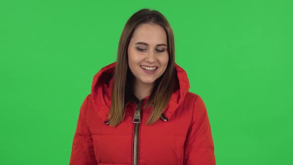 Portrait of Lovely Girl in a Red Down Jacket Is Coquettishly Smiling While Looking at Camera . Green