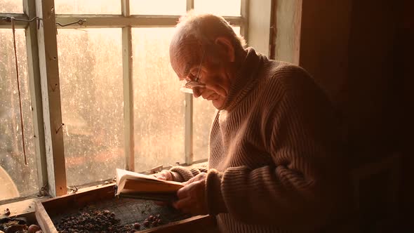 Man Glasses Picks Up Old Book in Dust Read in House Window