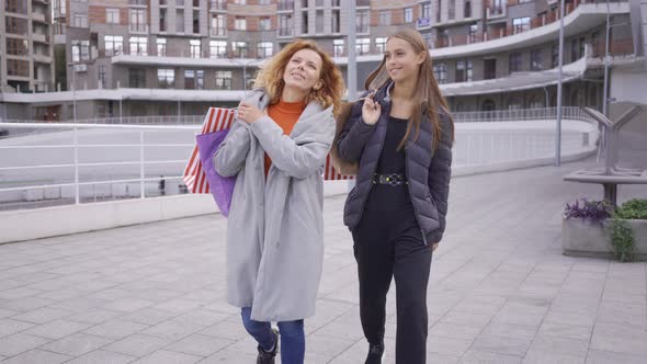 Two Happy Caucasian Girls Walking with Shopping Bags