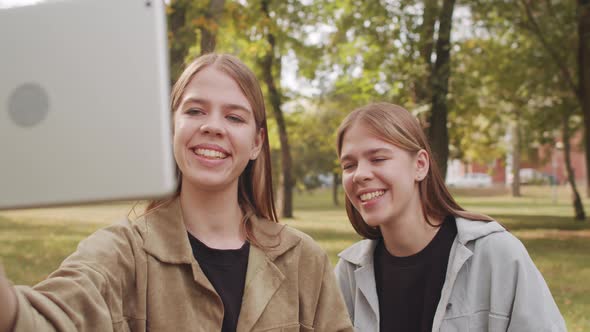 Happy Twin Sisters Video Calling in Park