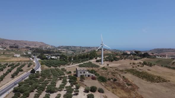 Cars Travelling On The Country Road Surrounded By The Green Olive Groves Near The Wind Farm - Wind T