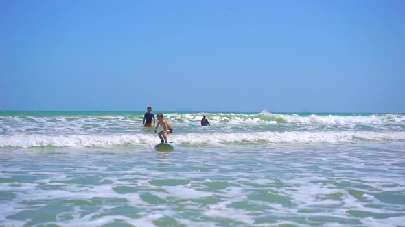 Surf Instructor Teaches Little Boy How To Surf. Slowmotion Shot