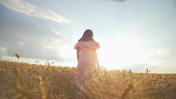 A Girl Takes a Romantic Stroll Through a Wheat Field at Sunset