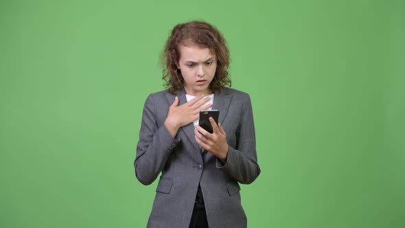 Young Stressed Businesswoman Using Phone and Looking Shocked