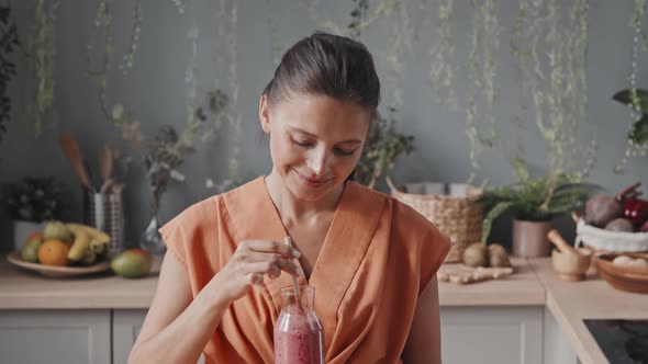 Portrait of Woman Tasting Smoothie in Kitchen