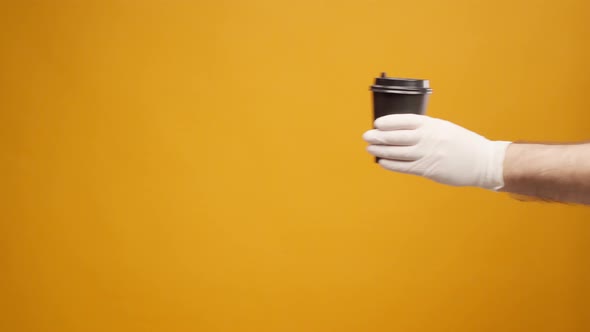 People's Hand Passing One Another Coffee to Go Coffee Delivery Against Yellow Background