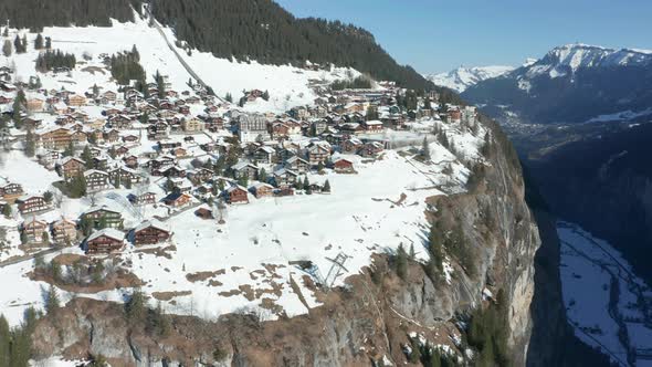 Flying towards snow covered town at the edge of mountain