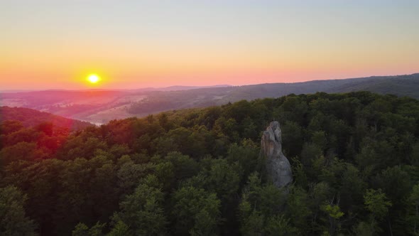 Aerial View of Bright Foggy Morning Over Dark Forest Trees and Big Rocky Boulders at Warm Summer