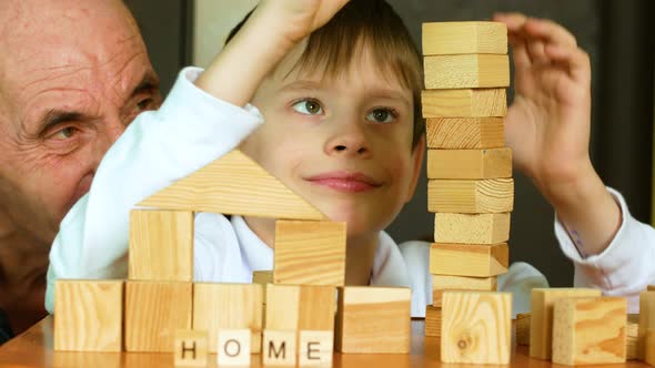 Educational joint board games theme. Caucasian pensioner and preschooler grandson building a tower f