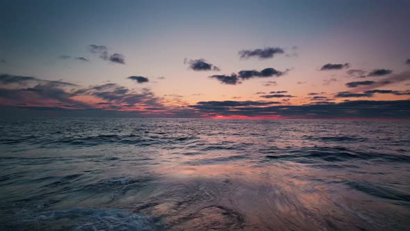 Drone Pulling Back Over Tide Coming In Over Beach At Sunset