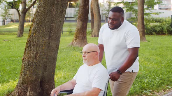 African-American caregiver and old disabled man in a wheelchair. Nurse and patient.