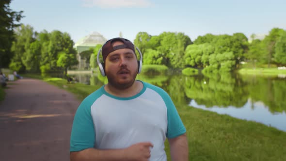 Fat Man Slowly Running in Summer Park Feeling Exhausted