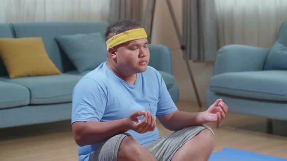 Fat Asian Man Doing Yoga In Easy Pose On Mat At Home