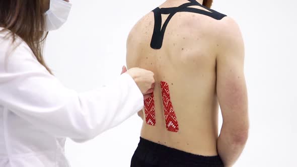 Doctor Video Footage - A Doctor Removing Kinesio Tape On The Back Of Her Patient