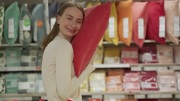 Brunette Chooses a Pillow on the Store Shelf