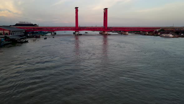 Red columns of Ampera bridge over Musi river, low angle drone fly view